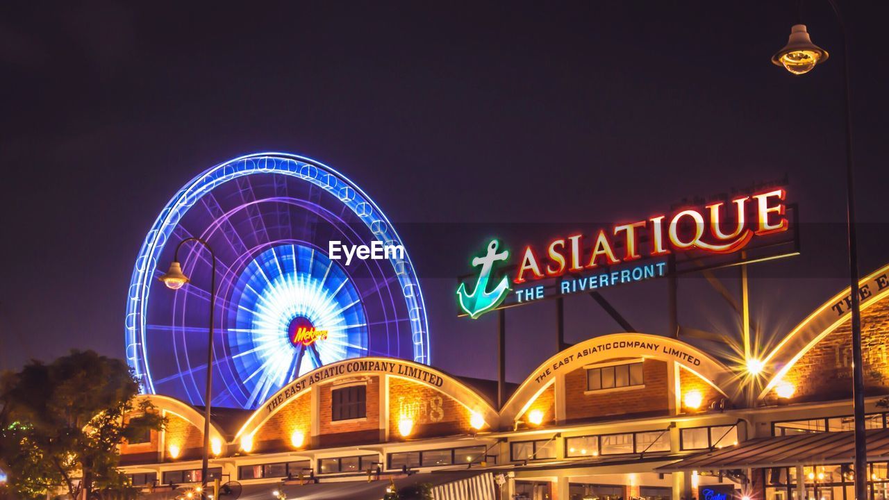 LOW ANGLE VIEW OF ILLUMINATED FERRIS WHEEL AGAINST CLEAR SKY AT NIGHT