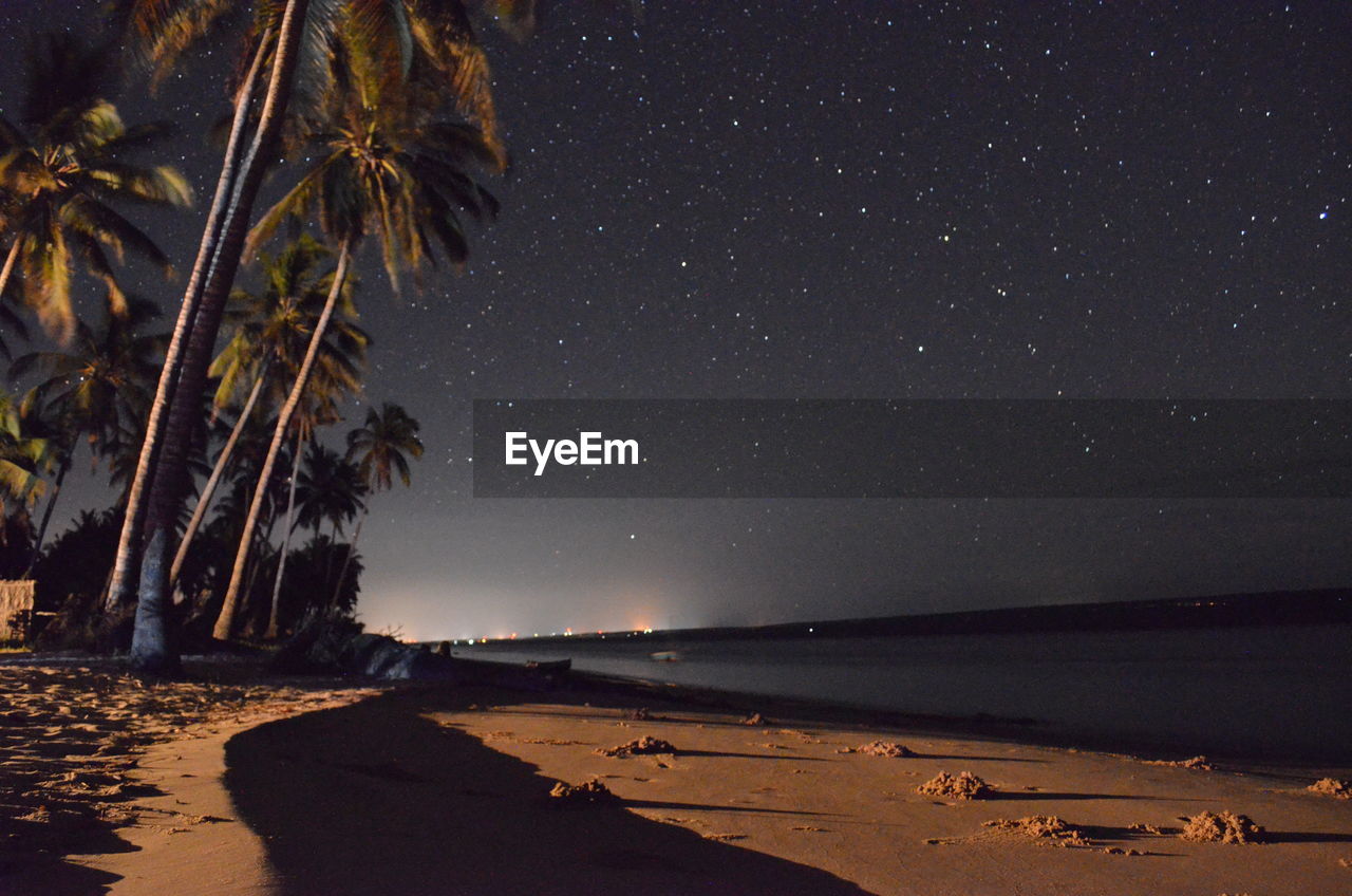 SCENIC VIEW OF BEACH AGAINST STAR FIELD AT NIGHT