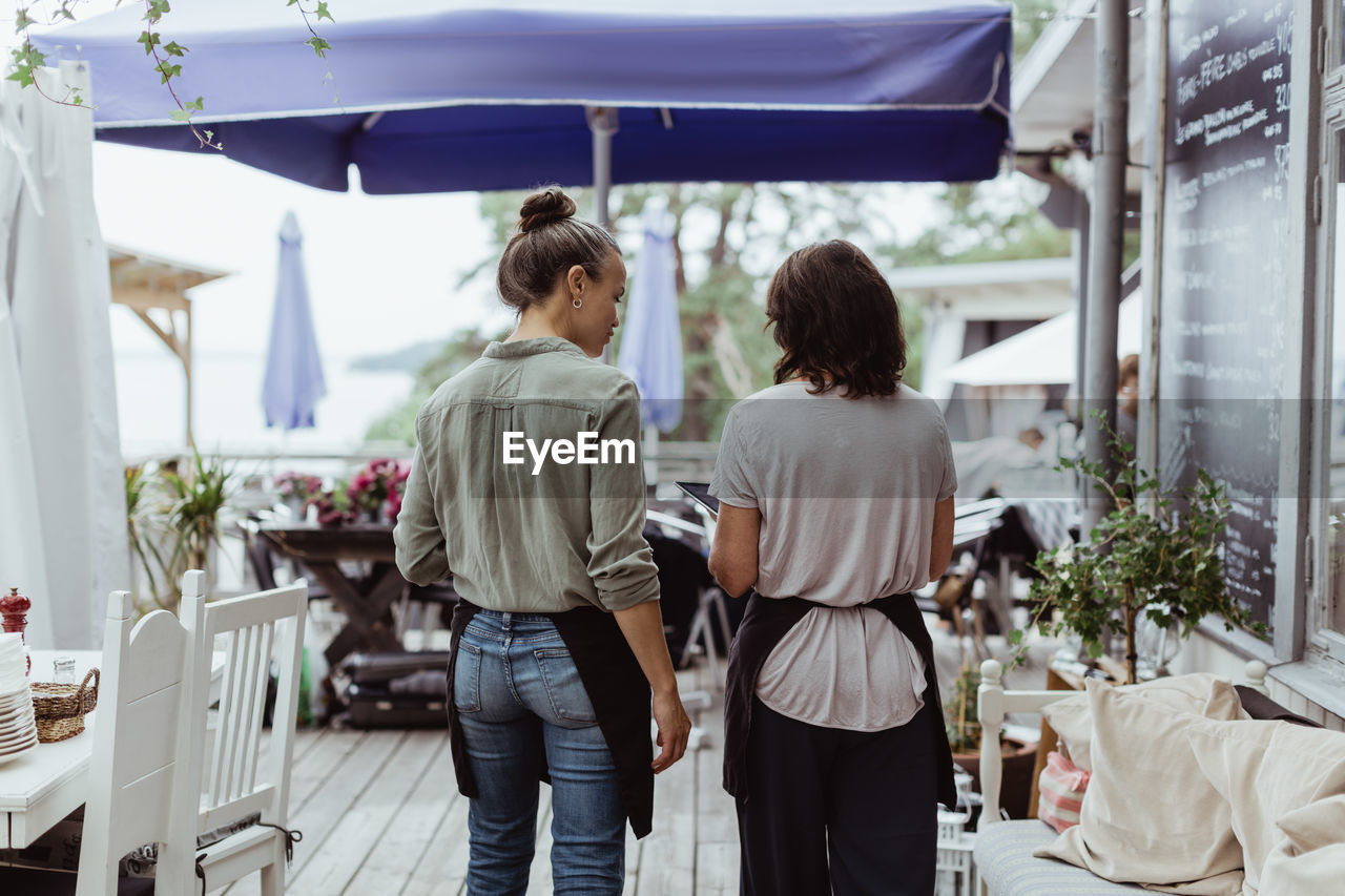 Rear view of businesswoman with coworker standing in restaurant