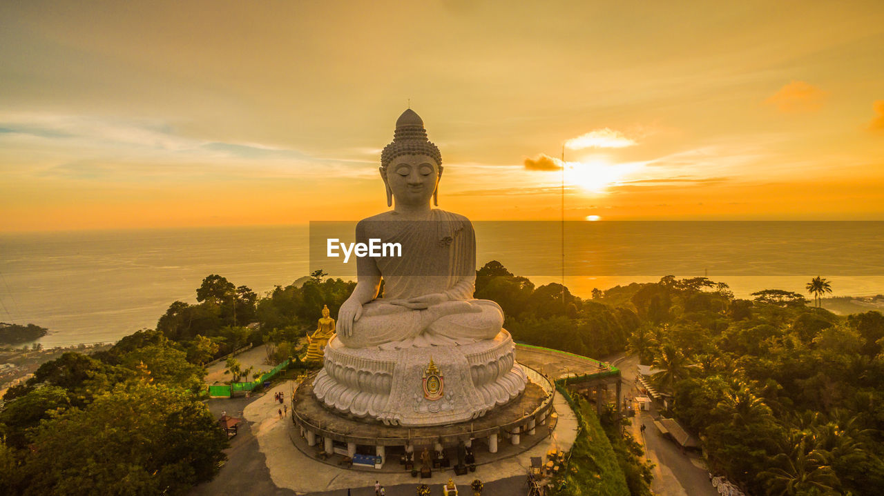 STATUE OF TEMPLE AGAINST BUILDING DURING SUNSET