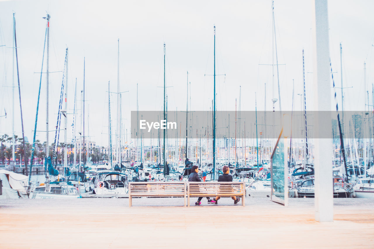 Boats moored at harbor against sky