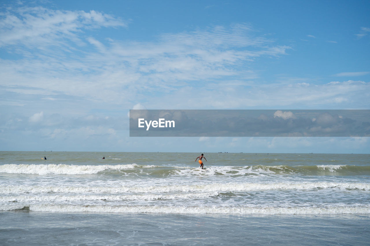 MAN SURFING ON SEA AGAINST SKY