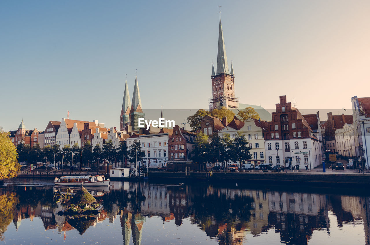 Buildings and church by river against sky in city