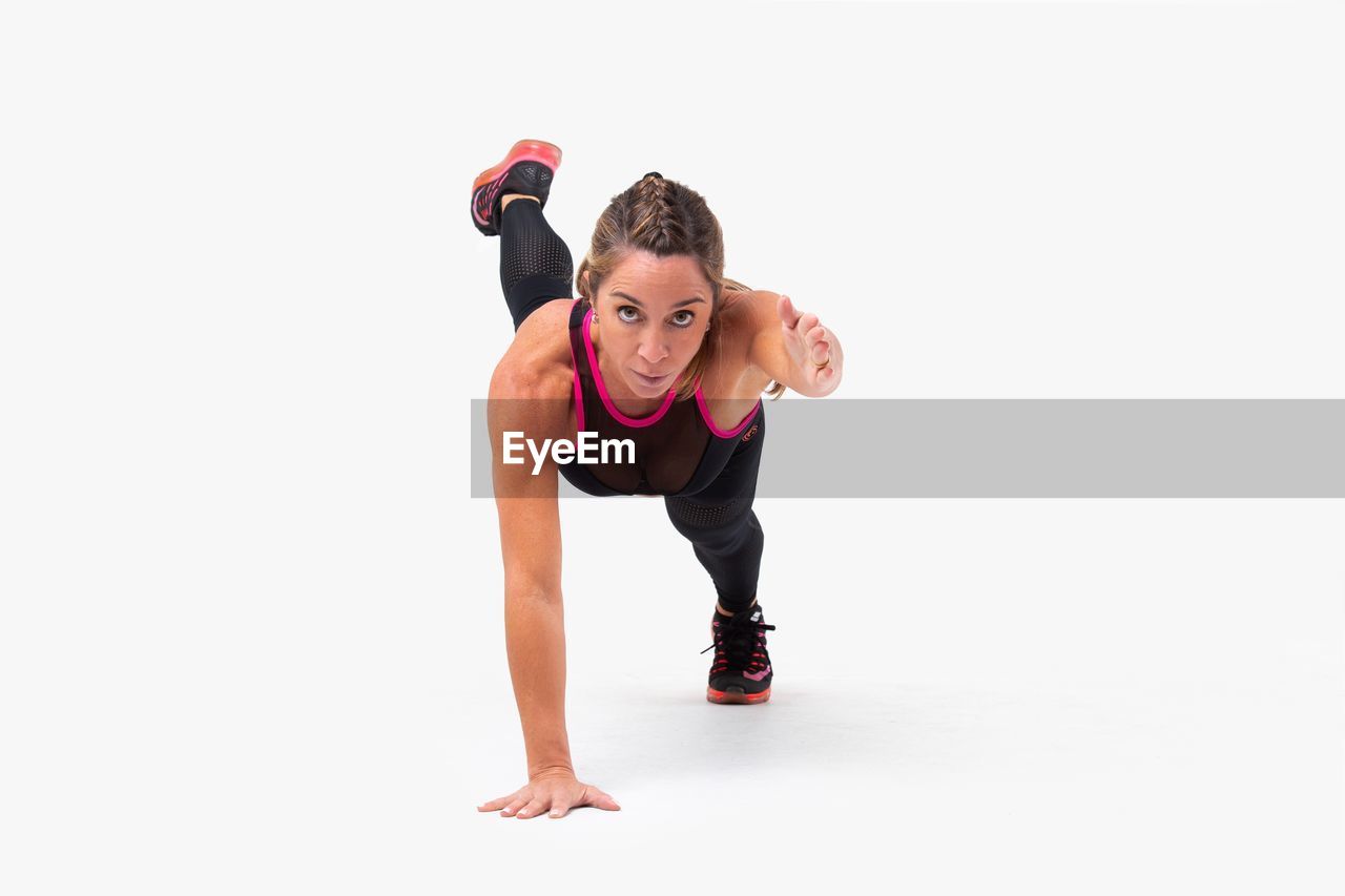 Portrait of woman exercising against white background