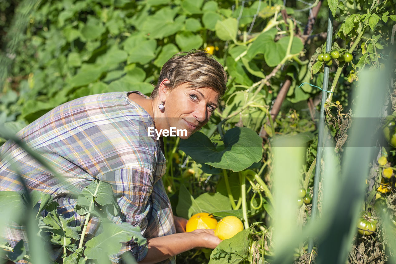 Portrait of smiling woman holding fruits at farm