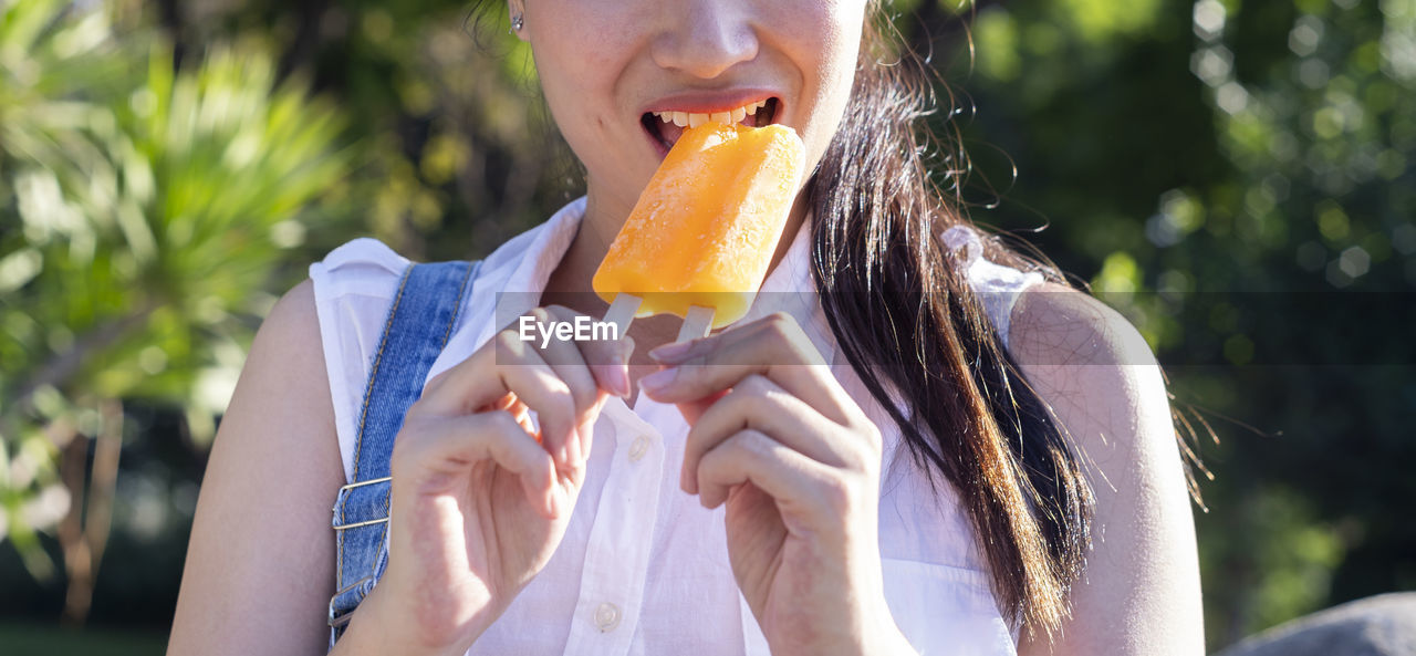 Midsection of woman eating ice-cream.