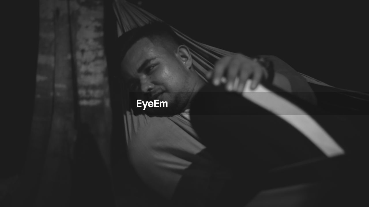 Man looking away while lying on hammock at night