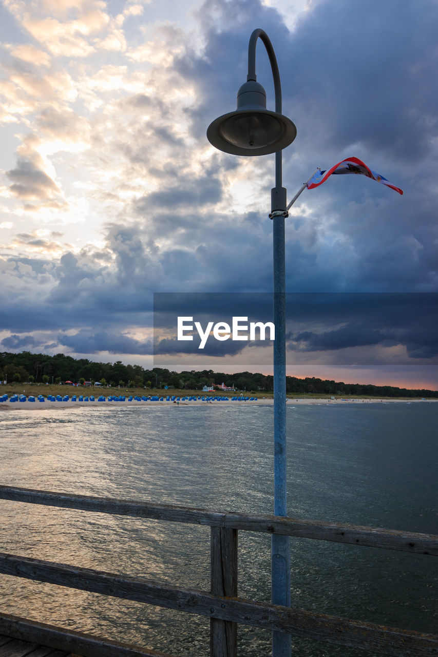 Street light by sea against sky