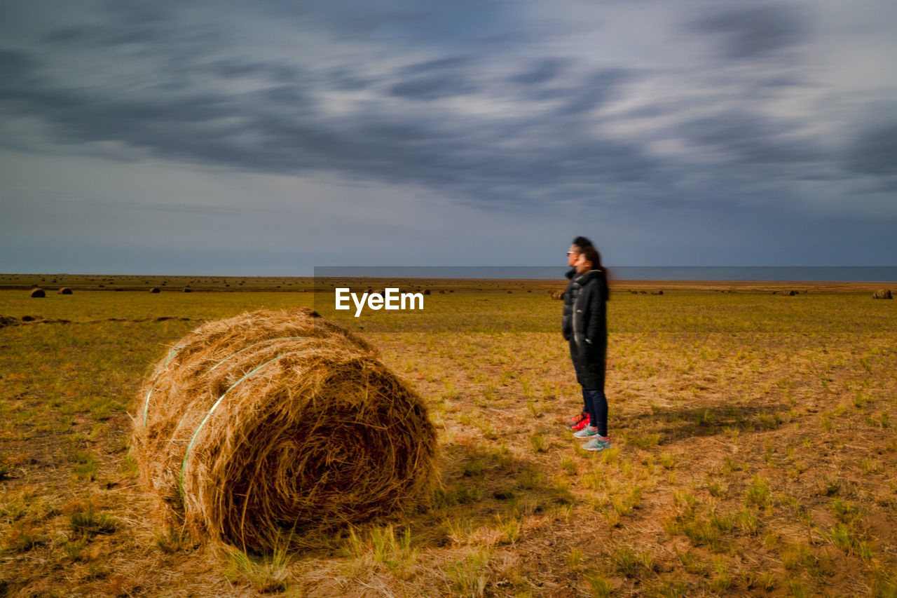 People standing by hay bale on agricultural field