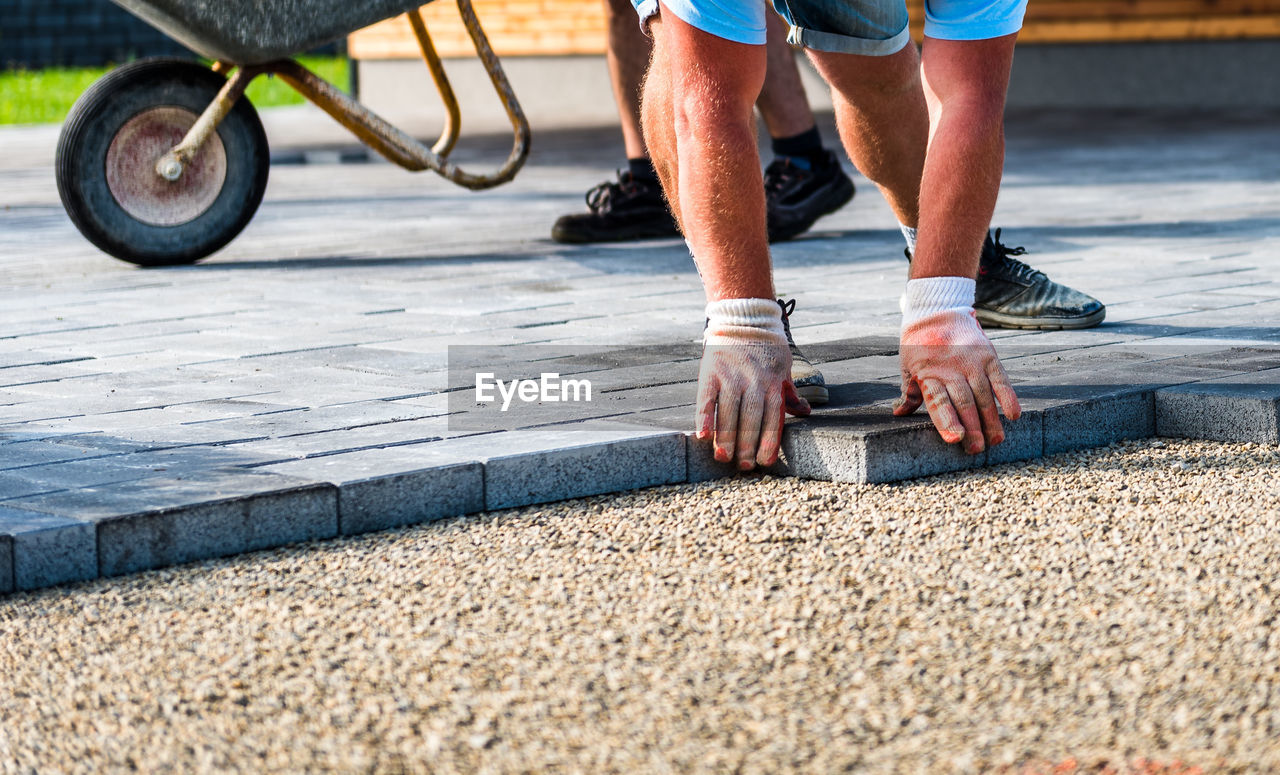 Construction worker arranging paving stones on street