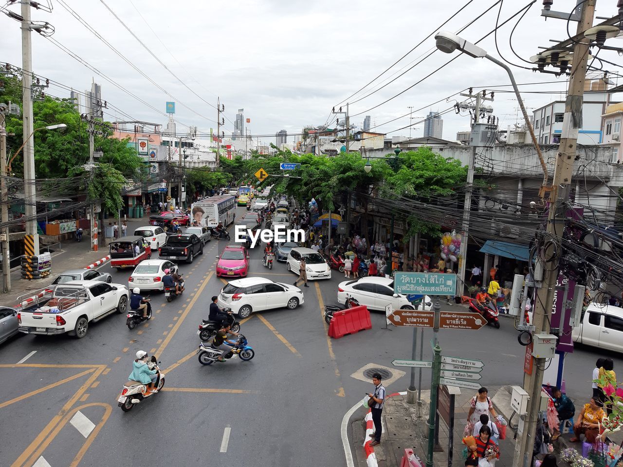 HIGH ANGLE VIEW OF VEHICLES ON ROAD ALONG BUILDINGS