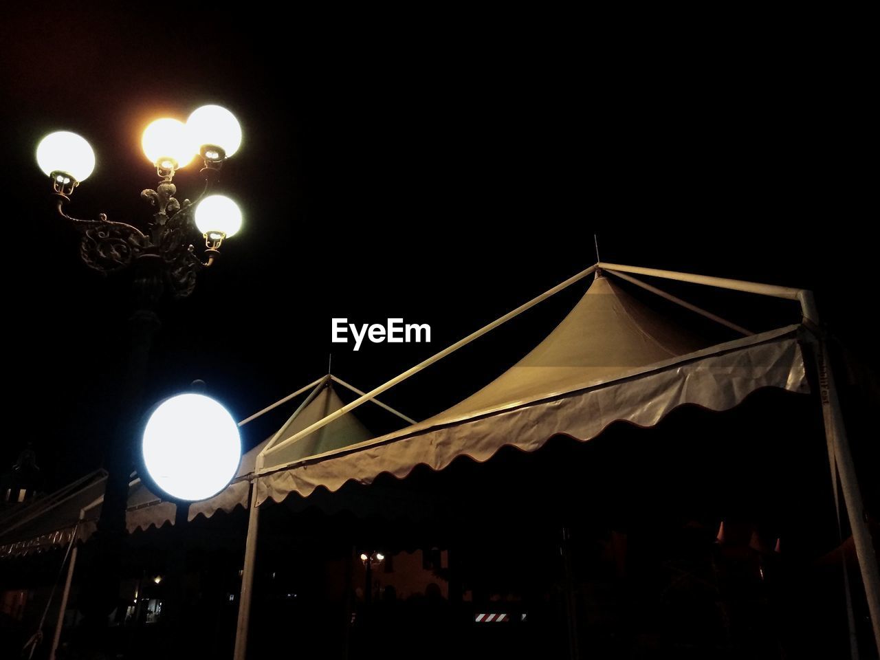 LOW ANGLE VIEW OF ILLUMINATED STREET LIGHTS AT NIGHT