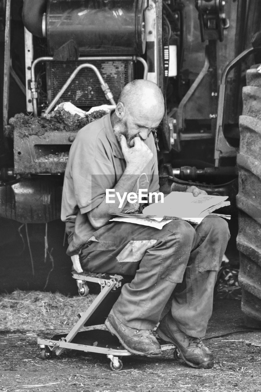 Man reading book while sitting in factory