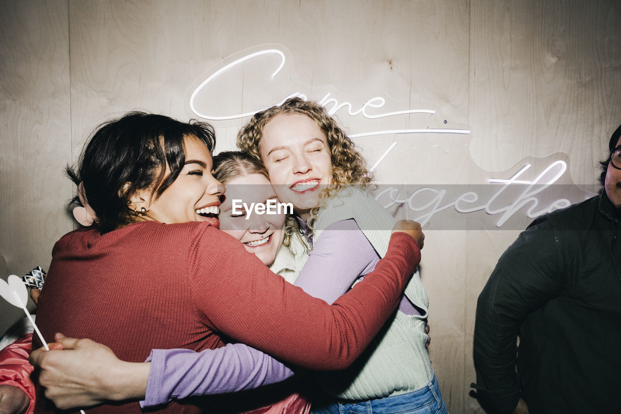 Happy multiracial female friends embracing each other in college dorm