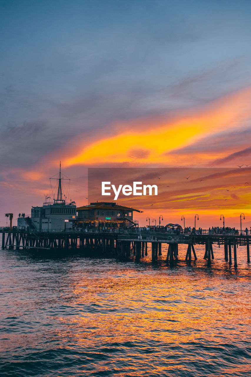 silhouette pier over sea against sky during sunset