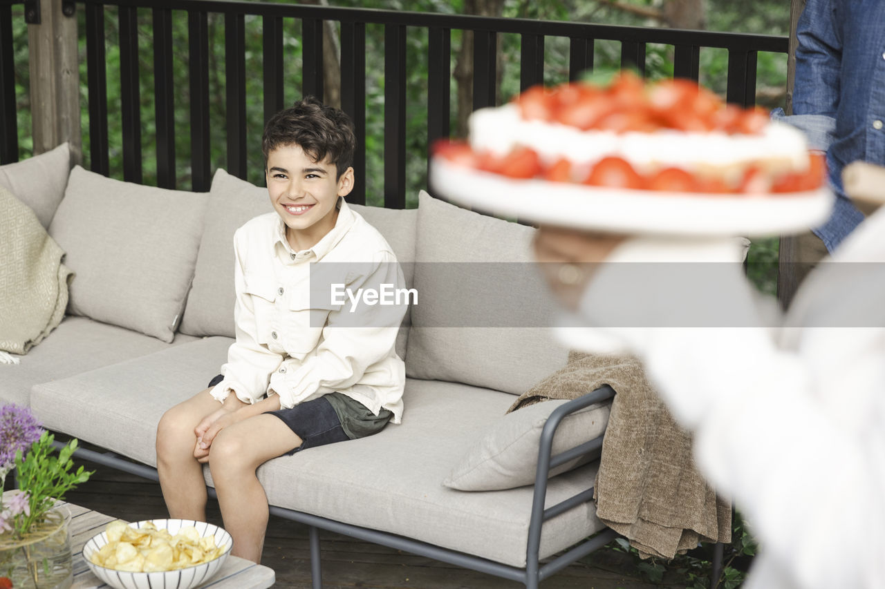 Smiling boy sitting on sofa at patio