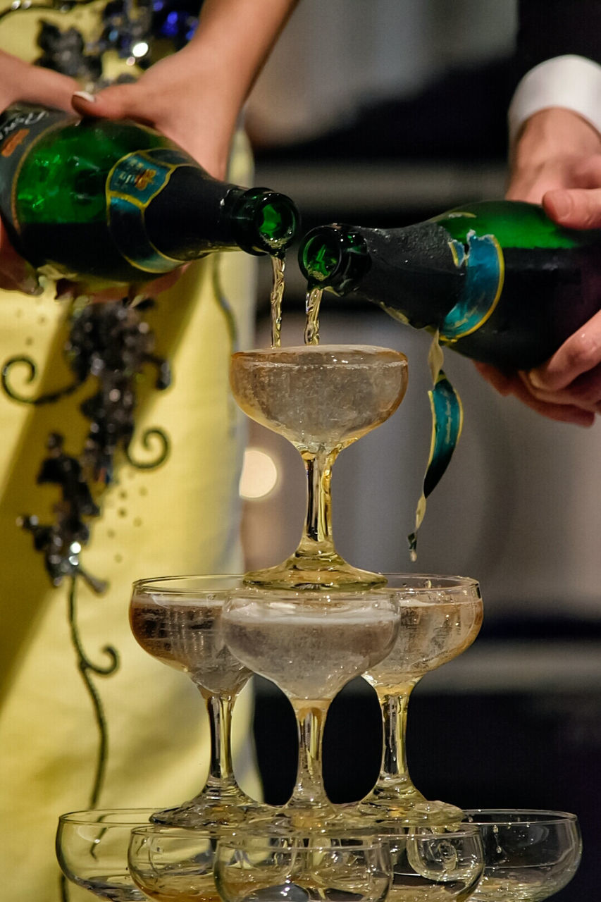 Midsection of people pouring champagne in stacked glasses