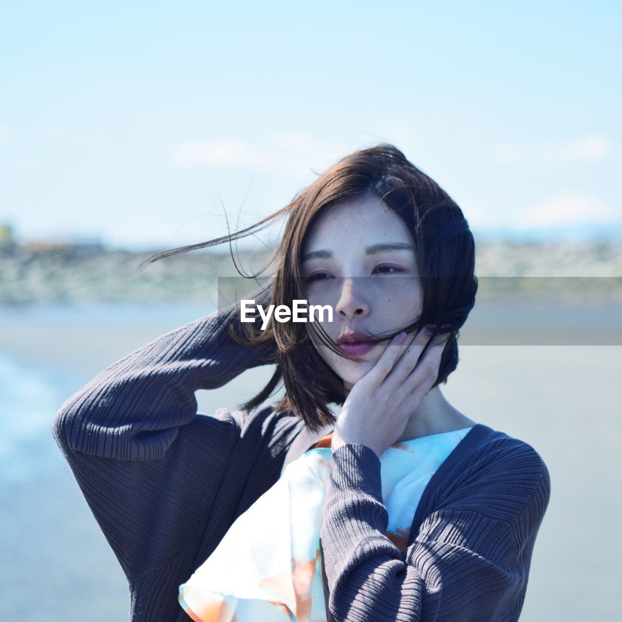 Portrait of beautiful young woman standing against sky
