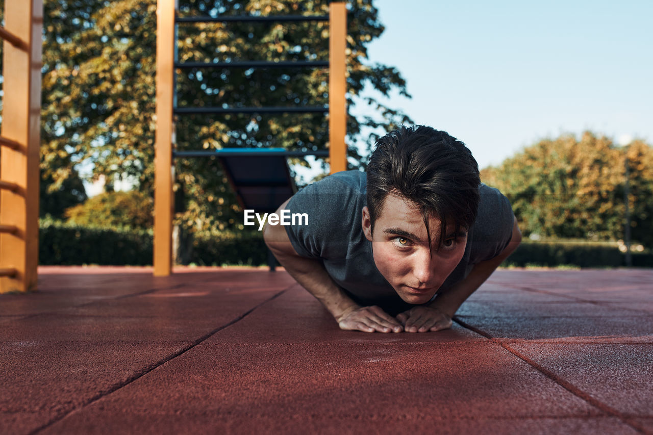 Young man doing push-ups on a red rubber ground during his workout