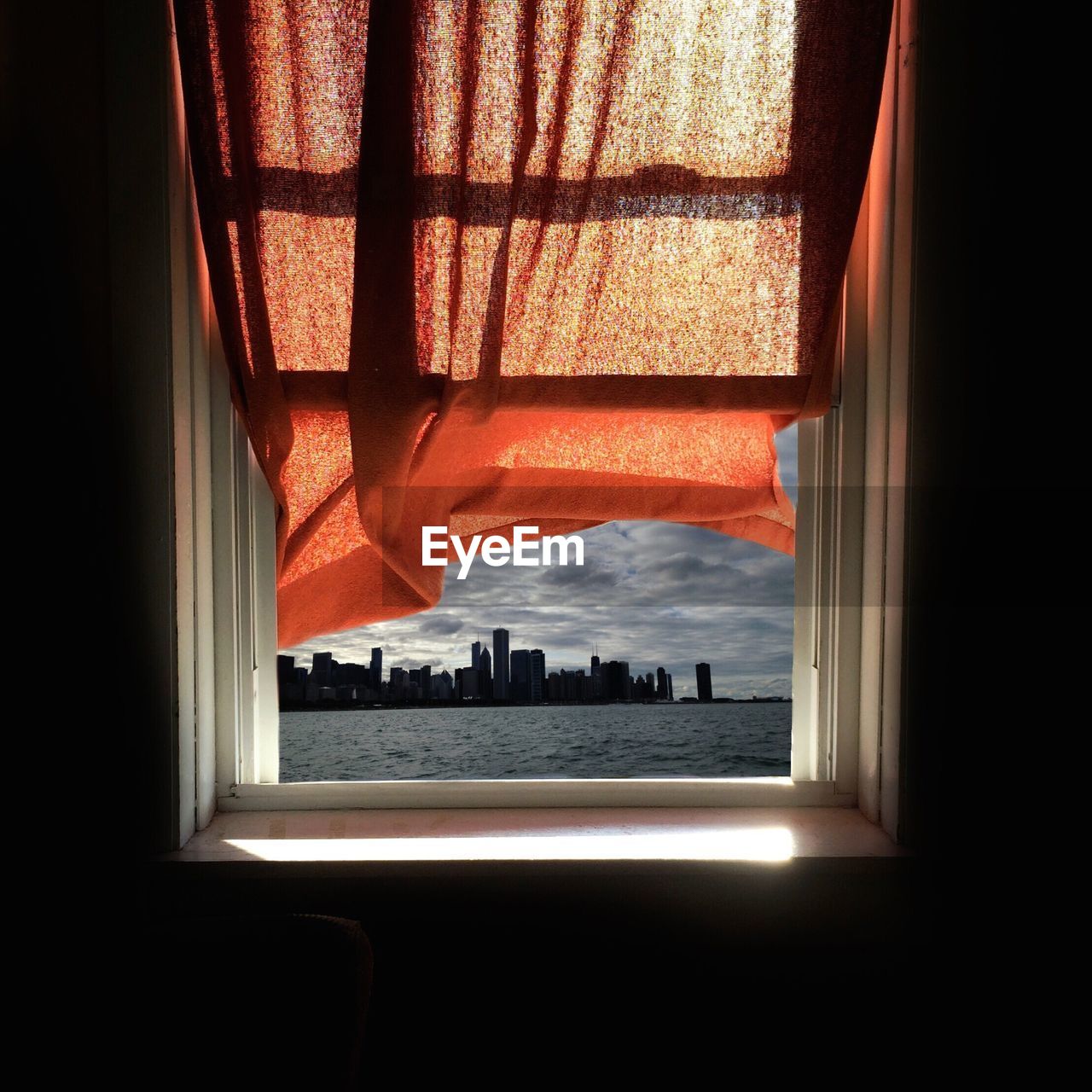 Window with red curtain looking to the city of skyscrapers