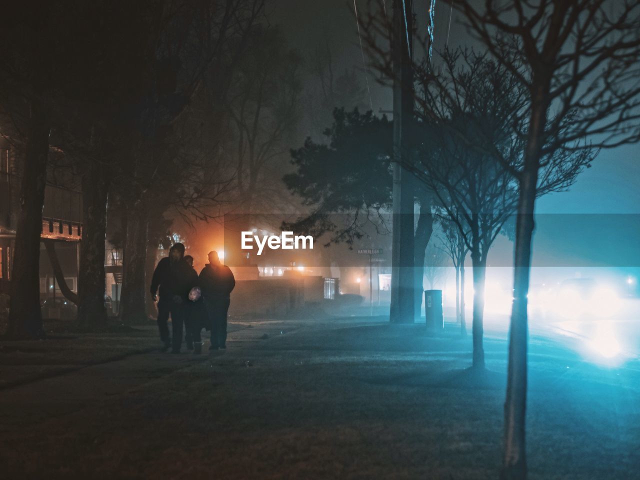 REAR VIEW OF MEN IN CITY AGAINST SKY AT NIGHT