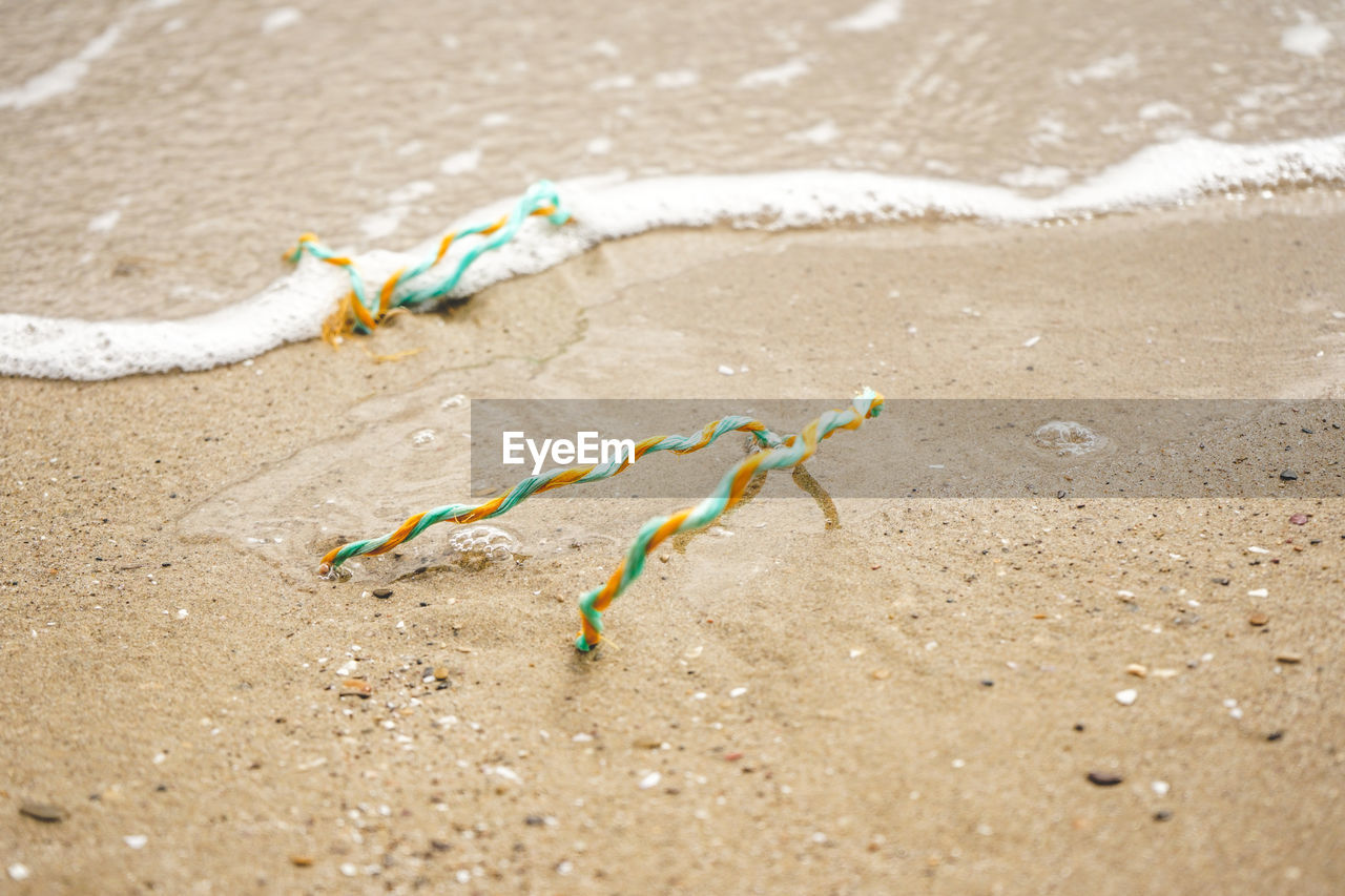 HIGH ANGLE VIEW OF LEAF ON SAND