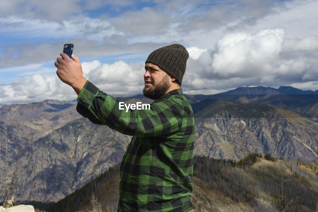 Male in flannel taking selfie with cell phone