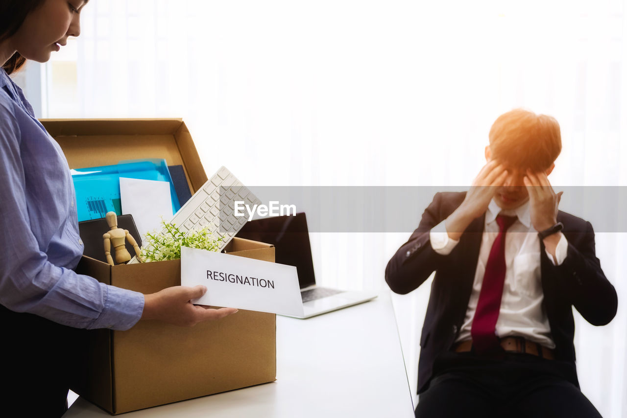 Woman giving resignation to businessman at desk in office