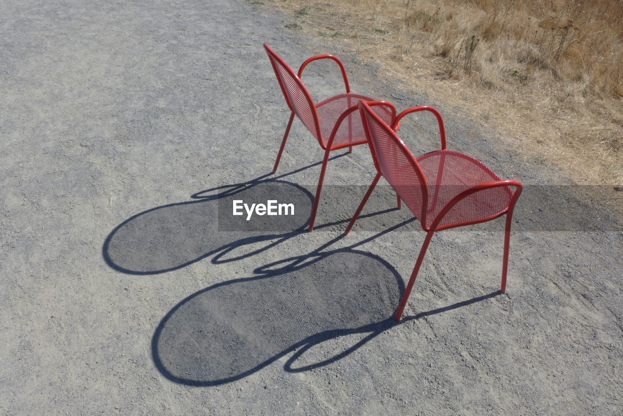 High angle view of red metallic chairs on dirt road