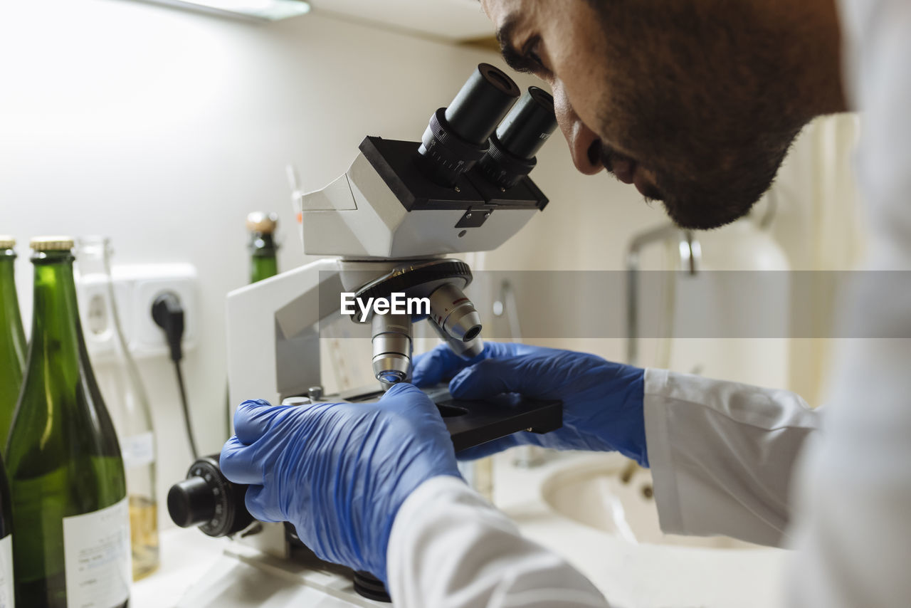 Winemaker analyzing a sample under a microscope in a winery lab.