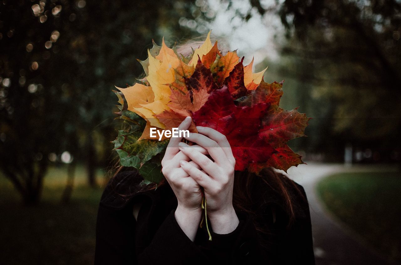 Close-up of woman covering face with leaves