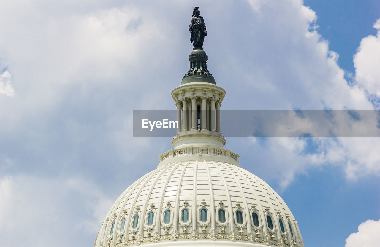 Low angle view of statue on dome against sky