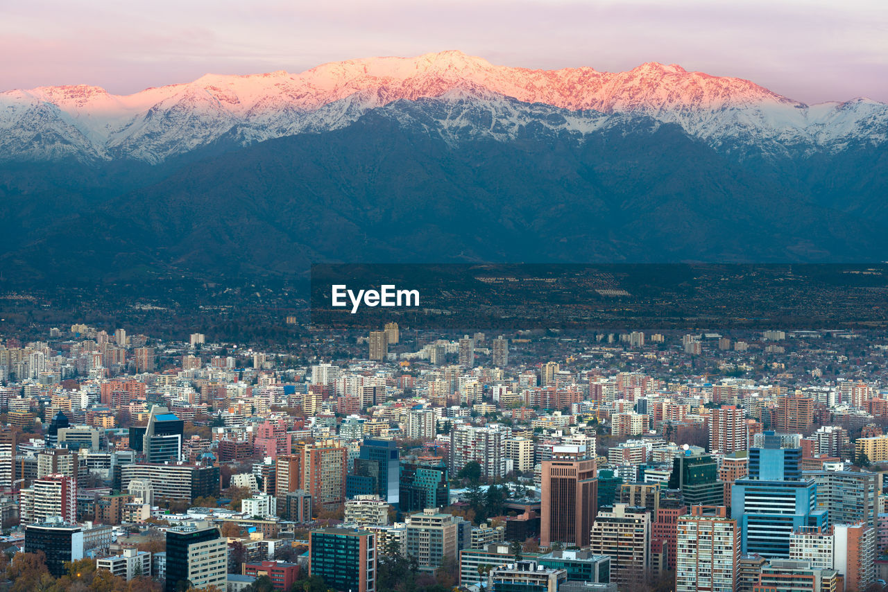 Aerial view of buildings in city against mountains during winter