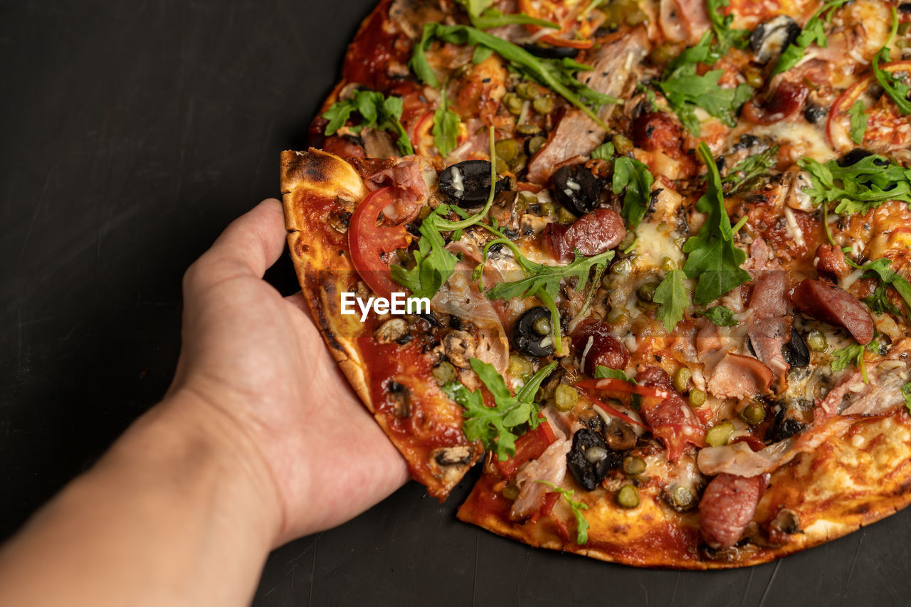 CROPPED IMAGE OF PERSON HOLDING PIZZA