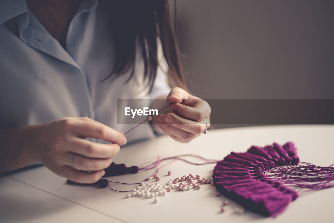 Woman working with threads and beads close-up, concept creativity, handicraft, hobby, toning