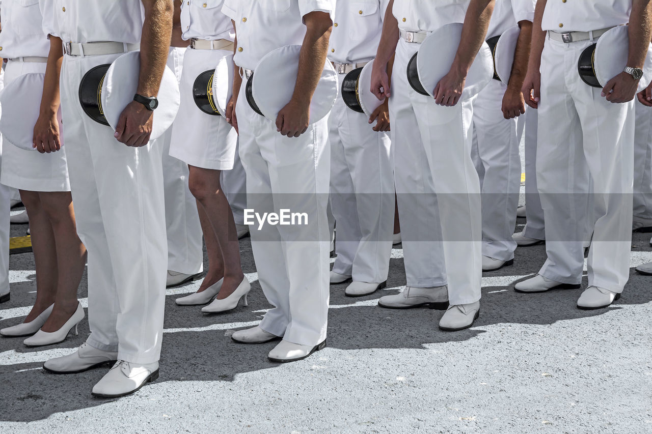 Low section of naval officers standing on ground during event