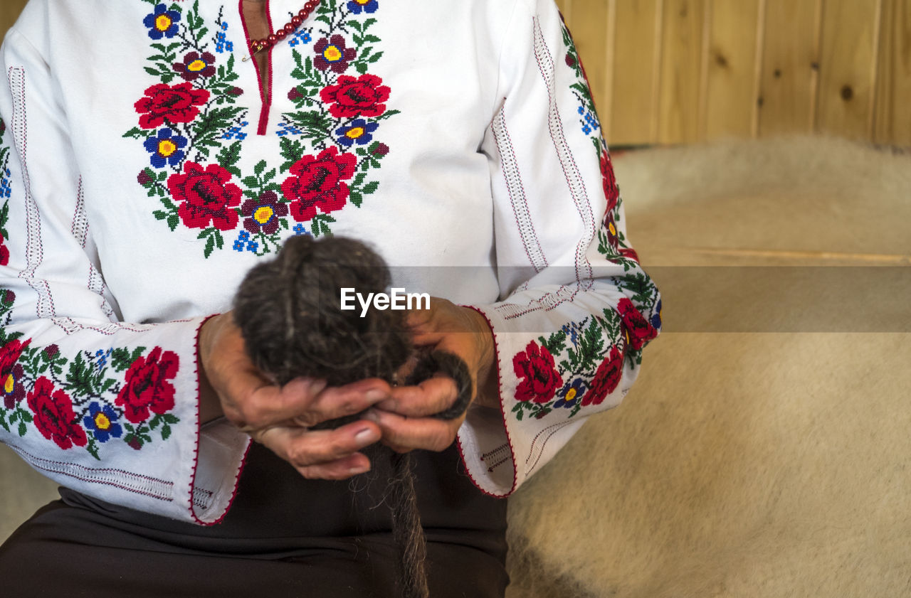 Midsection of woman holding ball of wool at home