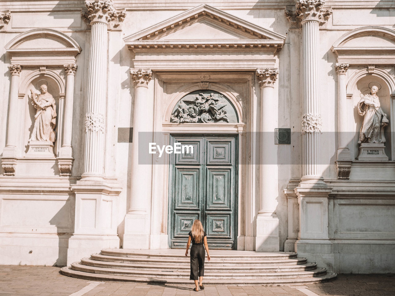 WOMAN STANDING ON STAIRCASE OF BUILDING