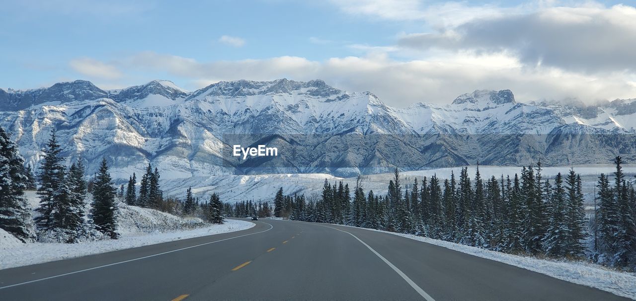 Road amidst snowcapped mountains against sky during winter