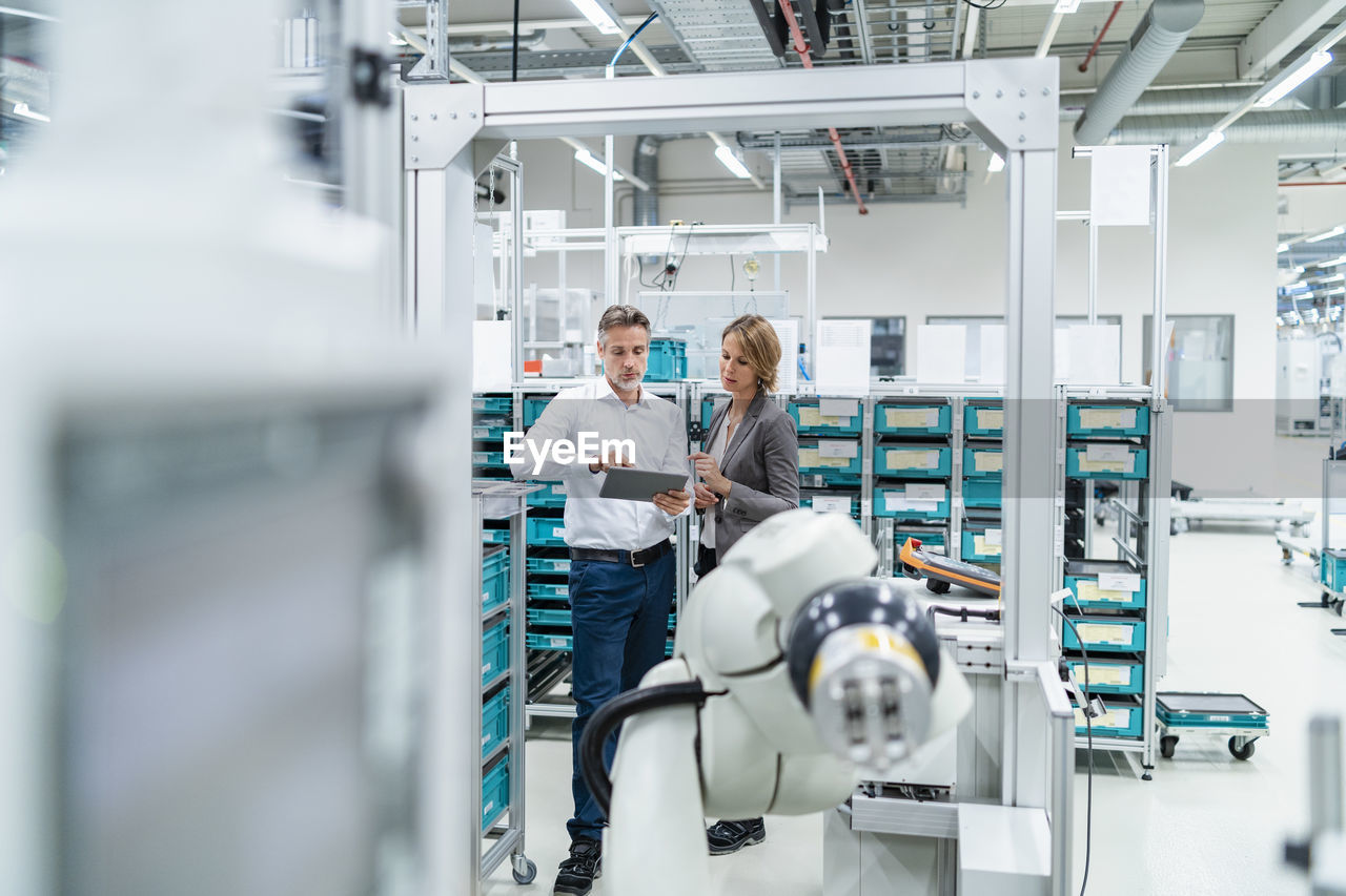 Businesswoman and manwith tablet talking in a modern factory