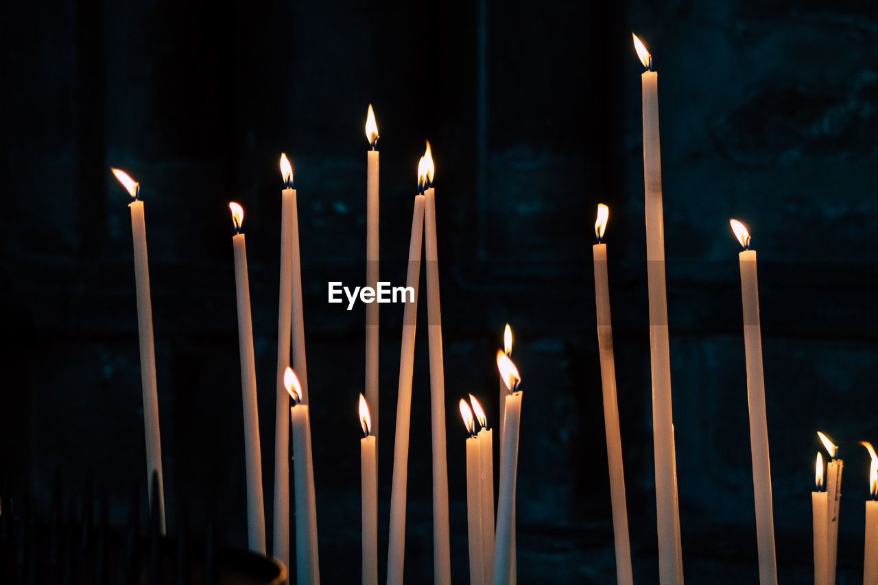 CLOSE-UP OF ILLUMINATED CANDLES AGAINST TEMPLE