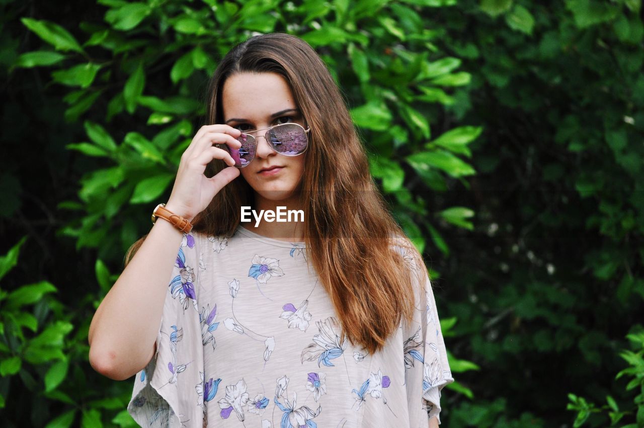 Portrait of teenage girl wearing sunglasses while standing against plants