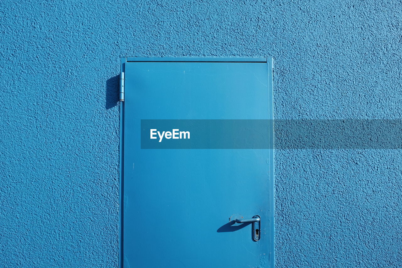 Close-up of closed door on blue wall