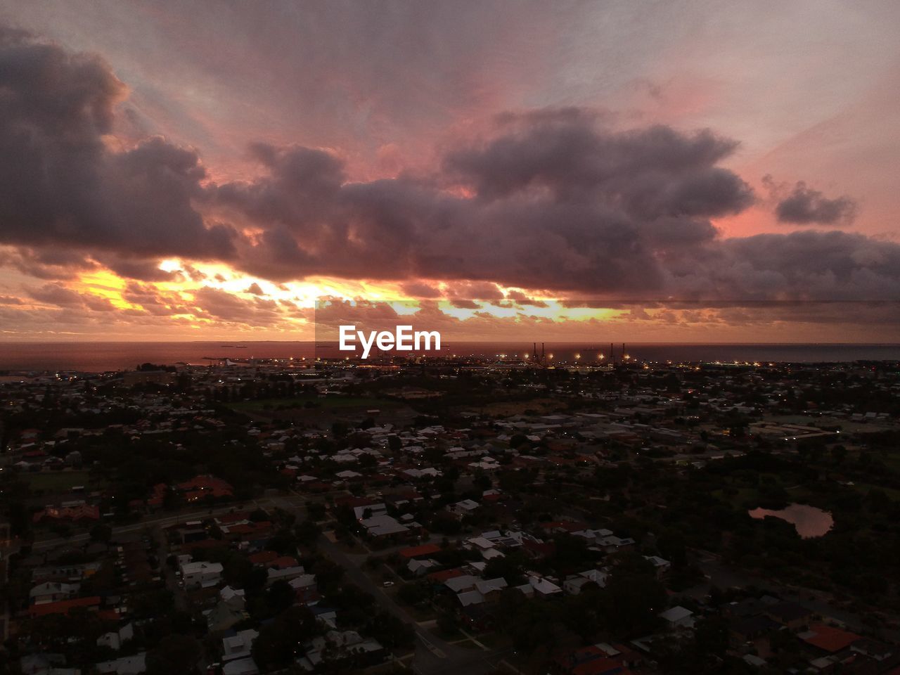 AERIAL VIEW OF CITY AND BUILDINGS AGAINST SKY DURING SUNSET
