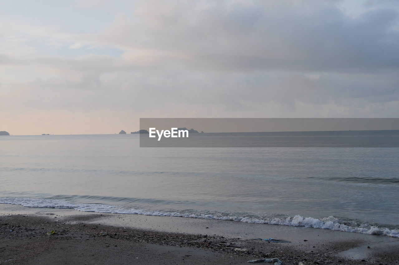 Scenic view of sea against cloudy sky at dusk