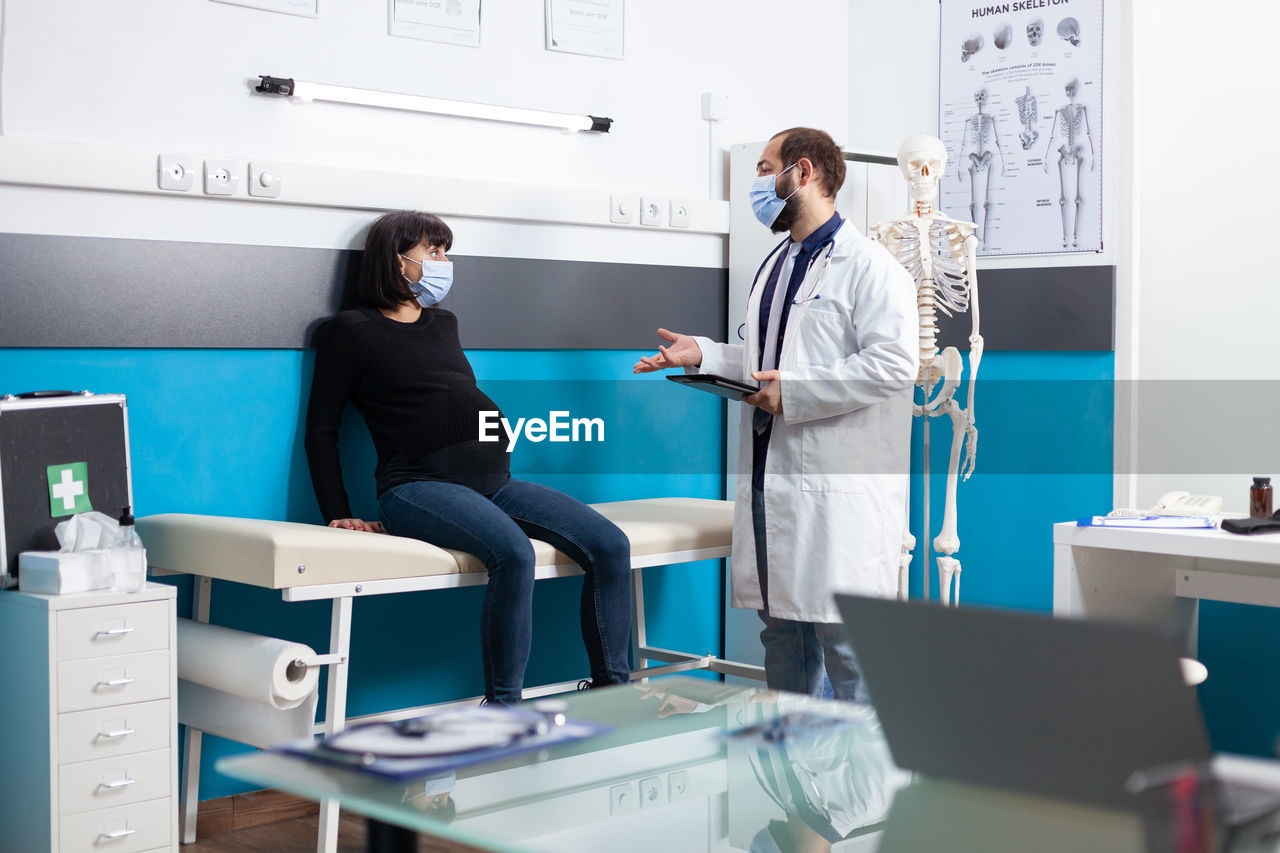 Doctor wearing mask examining patient in clinic