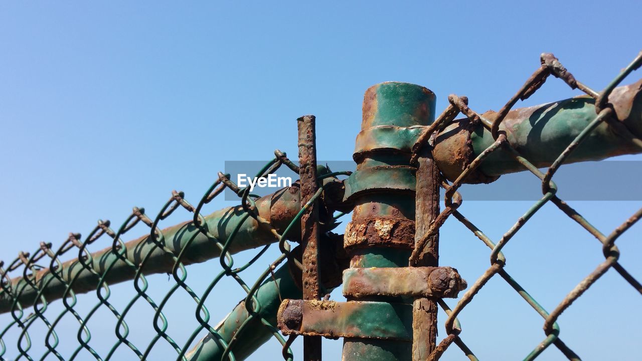 Low angle view of rusty metal against clear blue sky