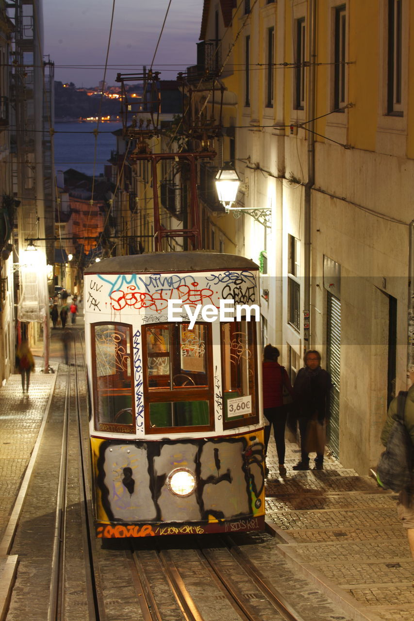 PEOPLE ON STREET IN ILLUMINATED CITY