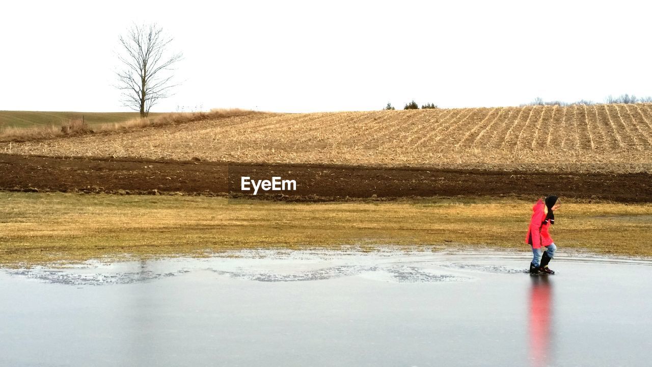 Girl wading in lake against agricultural field