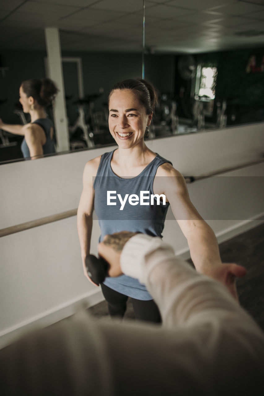 Smiling female personal trainer coaches a person lifting weights